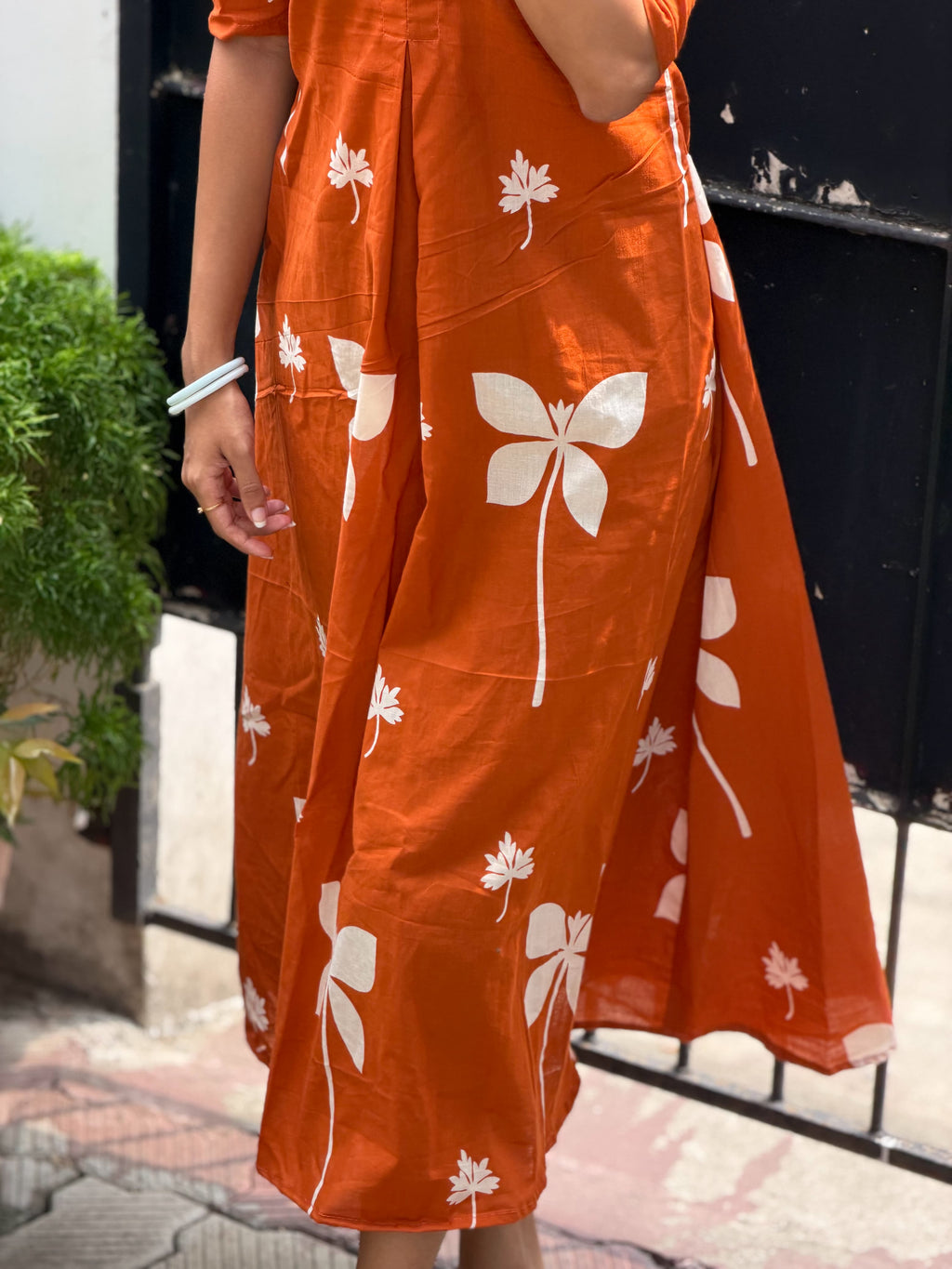 Hem and skirt detail of [PBC1021] Rust Orange Botanical Frill Dress – showing bold white floral print and drape
