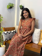 [PBC1036] Rust Paisley Hand-Block Jaipur Soft Cotton – model seated on bench showing full dress length and paisley print