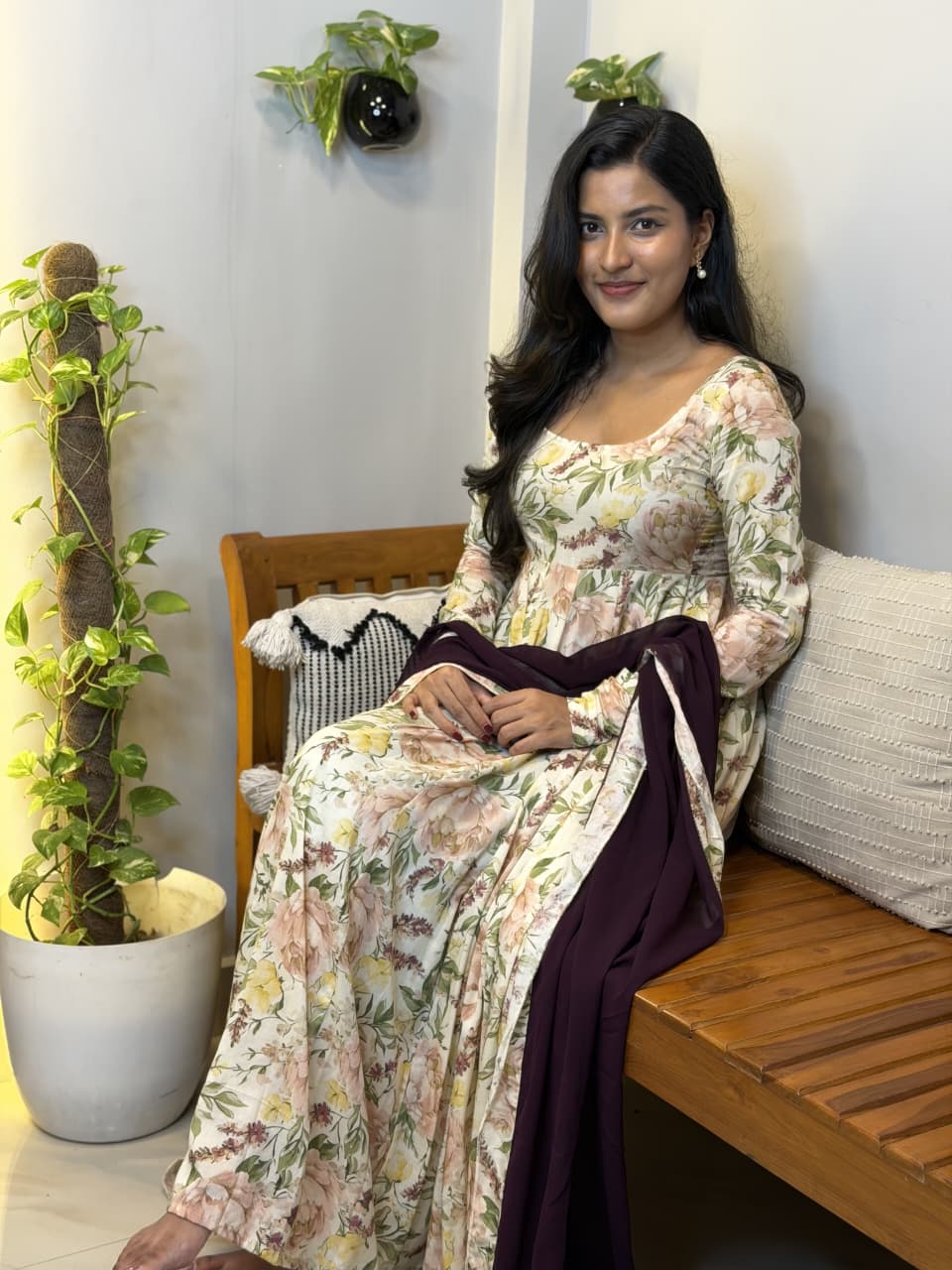 [PBC1037] Ivory Garden Floral Muslin Cotton – model seated on bench with plum dupatta, showing full dress and print