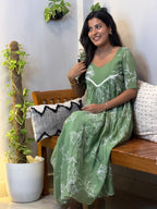 [PBC1038] Sage Green Floral Outline Mul Chanderi – model seated on bench showing upper body and white floral outline detail